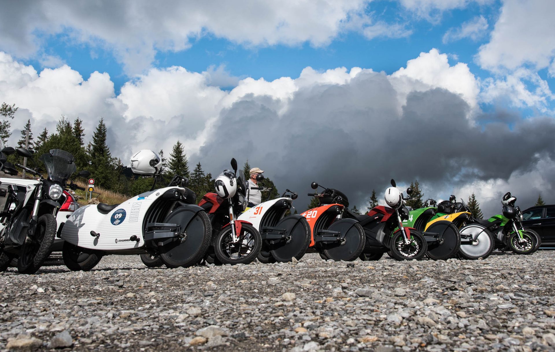 Elektromotorräder – Johammer und Zero – aufgereiht auf einem Alpenpass vor Wolkenkulisse
